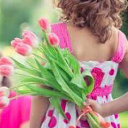 Girl in dress holding flowers behind back