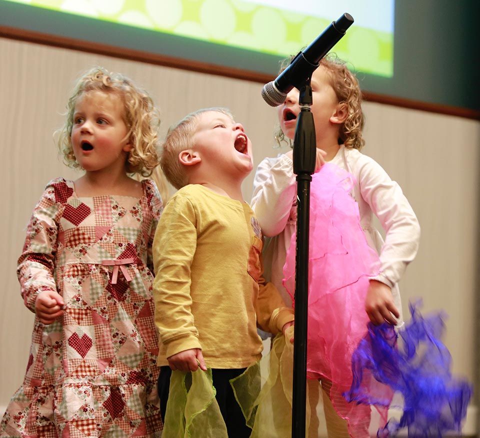 Children on stage singing at the KidZone's Think Big fundraiser