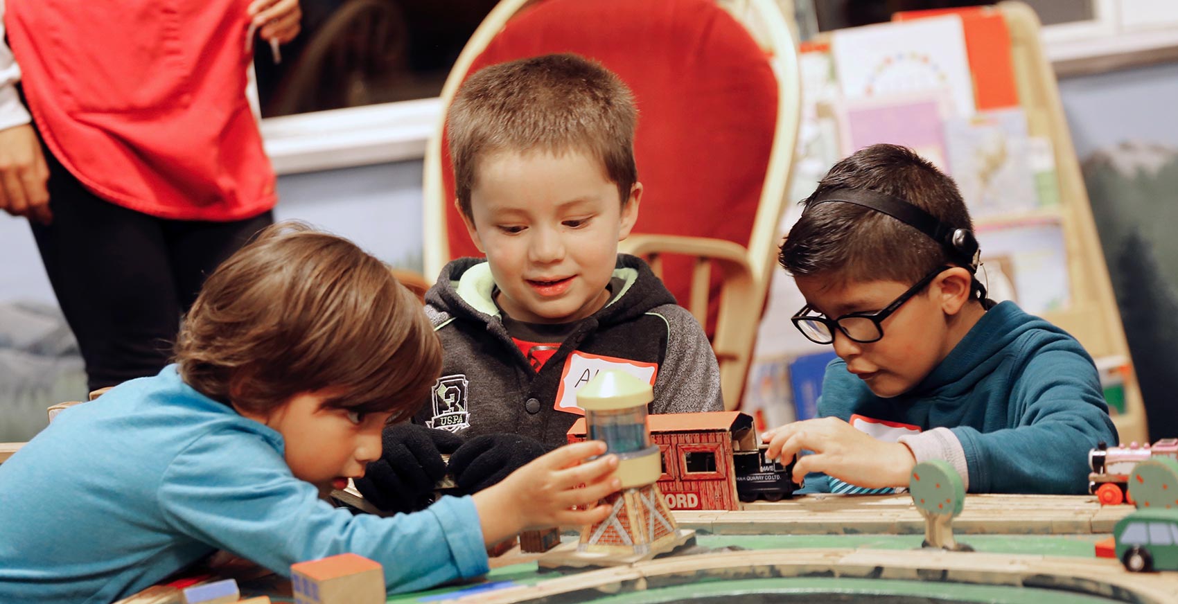 Three kids play together on the train table at Special Night at the Museum