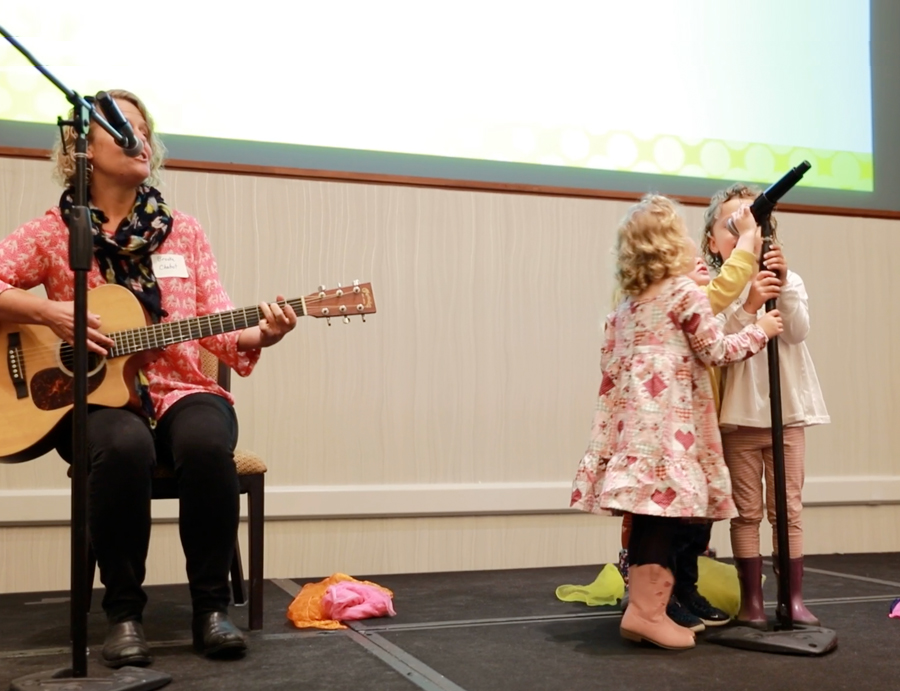 Brooke Chabot, M.A., Piano Instructor/Music Educator singing on stage with children